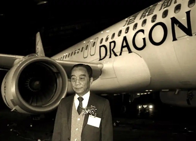 曹光彪在港龙航空客机前留影，机身上 DRAGON 字样清晰可辨